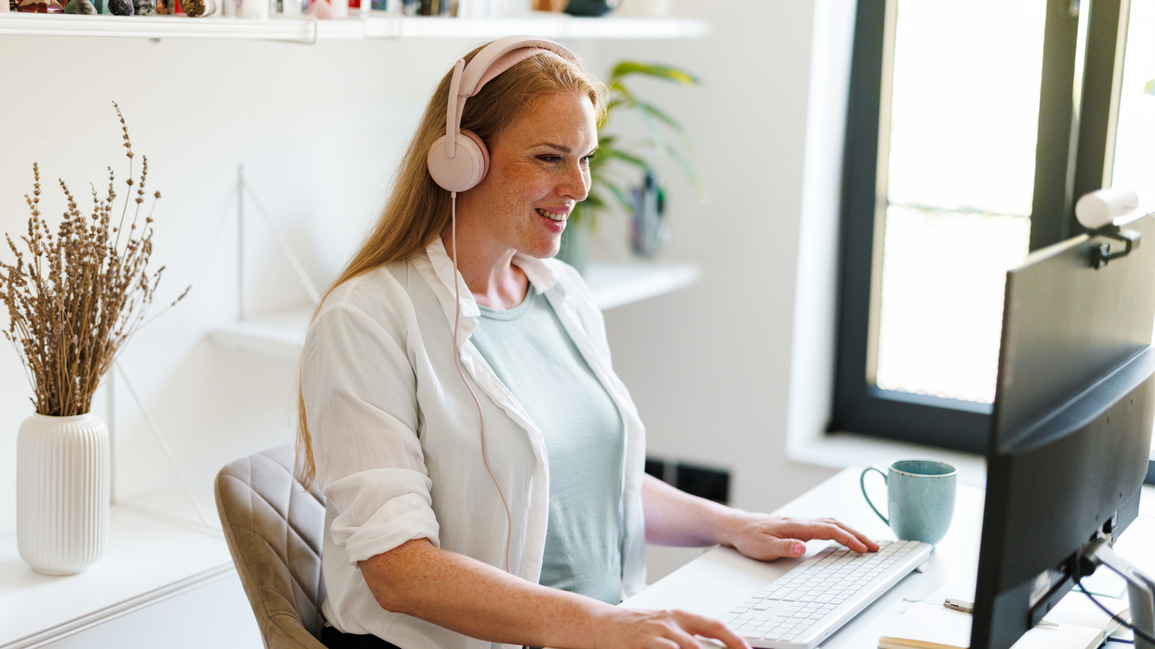 Une femme portant un casque est assise à un bureau, tapant sur un clavier.