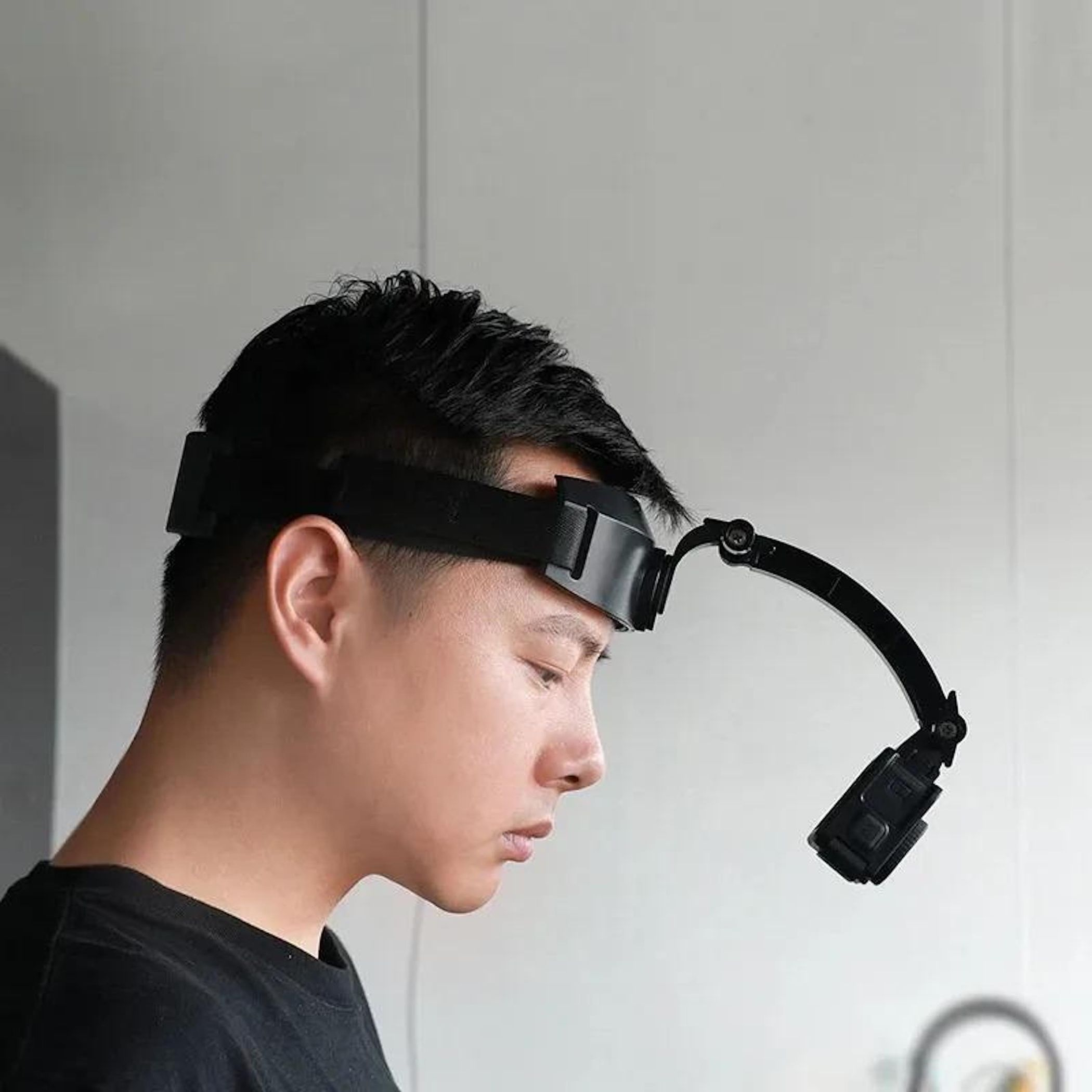 Ein Mann mit Stirnlampe, im Profil fotografiert, trägt ein schwarzes T-Shirt.