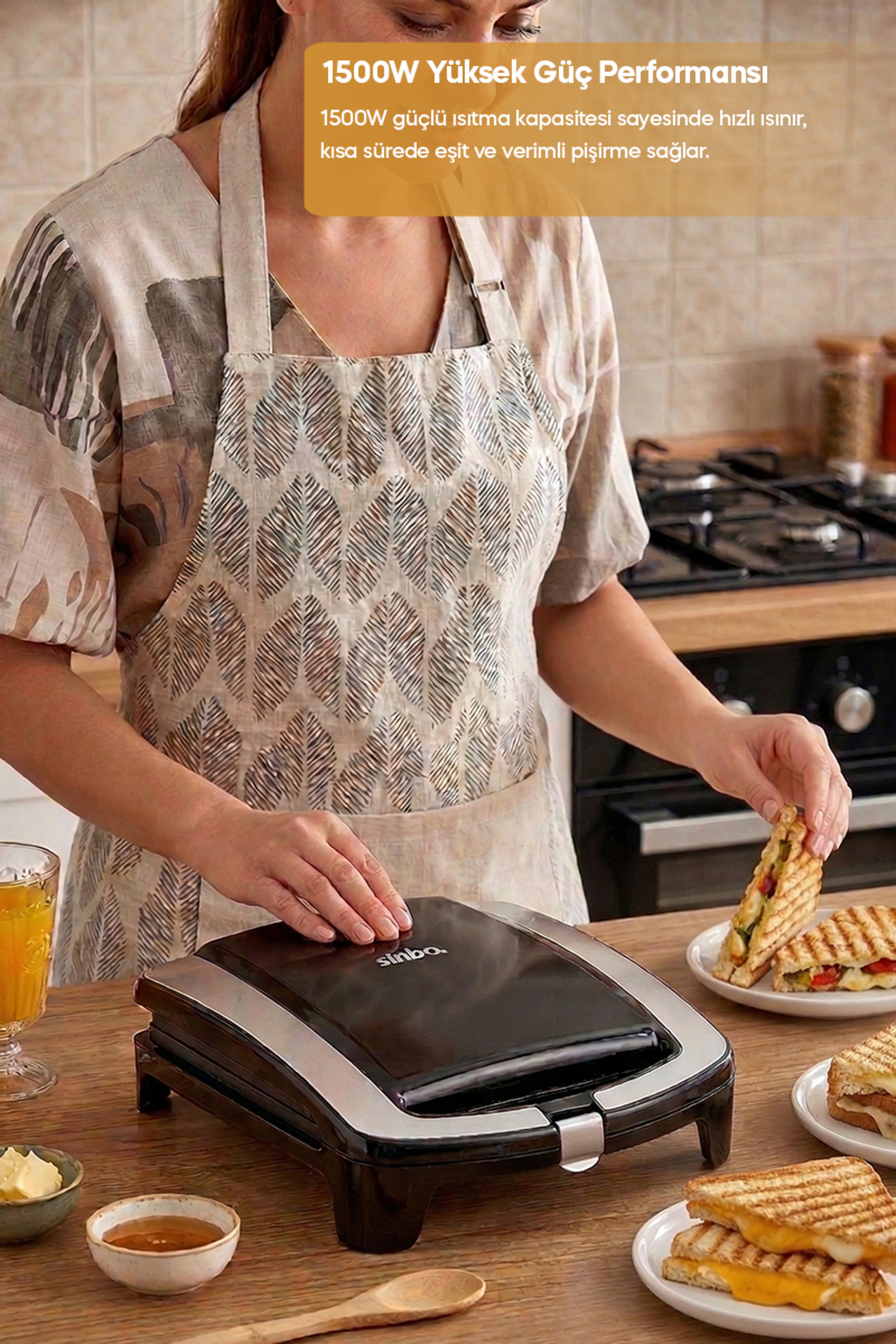 Bir kişi yanında bir bardak portakal suyu ile tost makinesinde sandviç yapıyor.