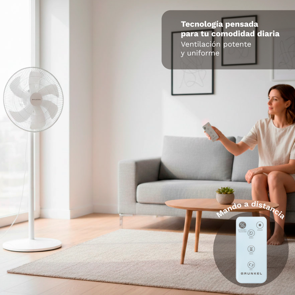 Un ventilador blanco de pie está a la izquierda. Una mujer sentada en un sofá sostiene un mando.