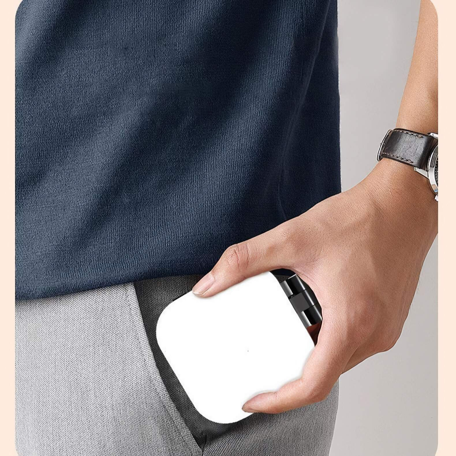 Eine Hand hält ein weißes Ladegerät in einer grauen Hosentasche.