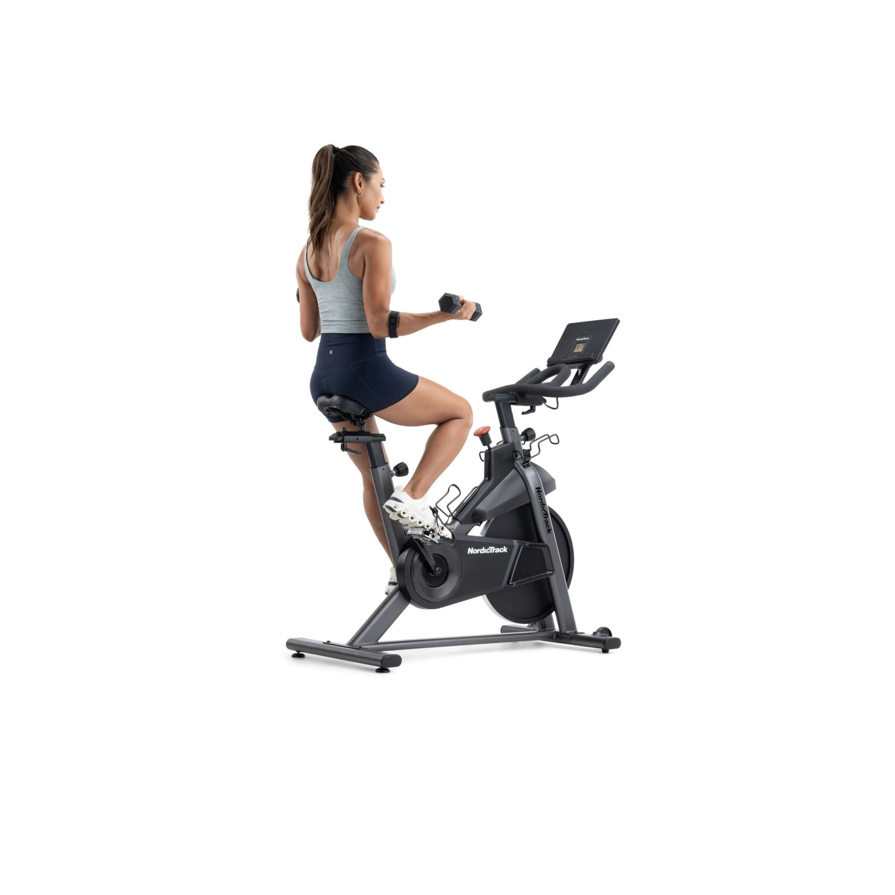 Eine Frau sitzt auf einem Heimtrainer und hebt Hanteln.