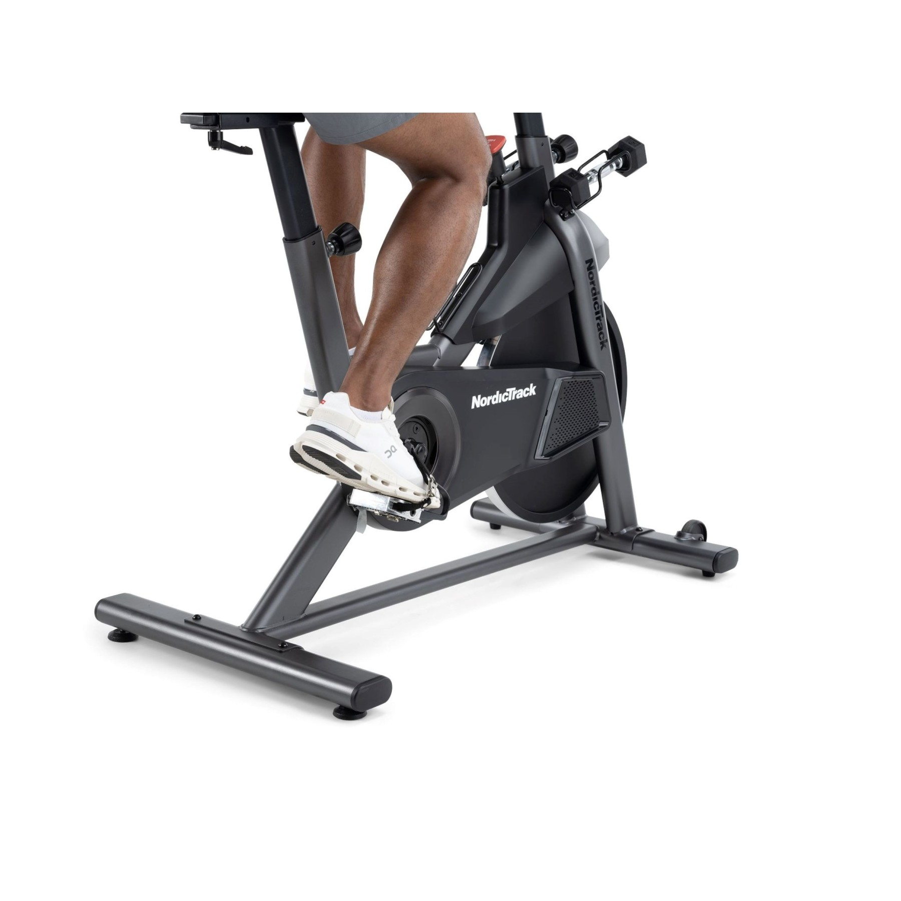 Beine einer Person auf einem grauen NordicTrack-Heimtrainer in weißen Schuhen.