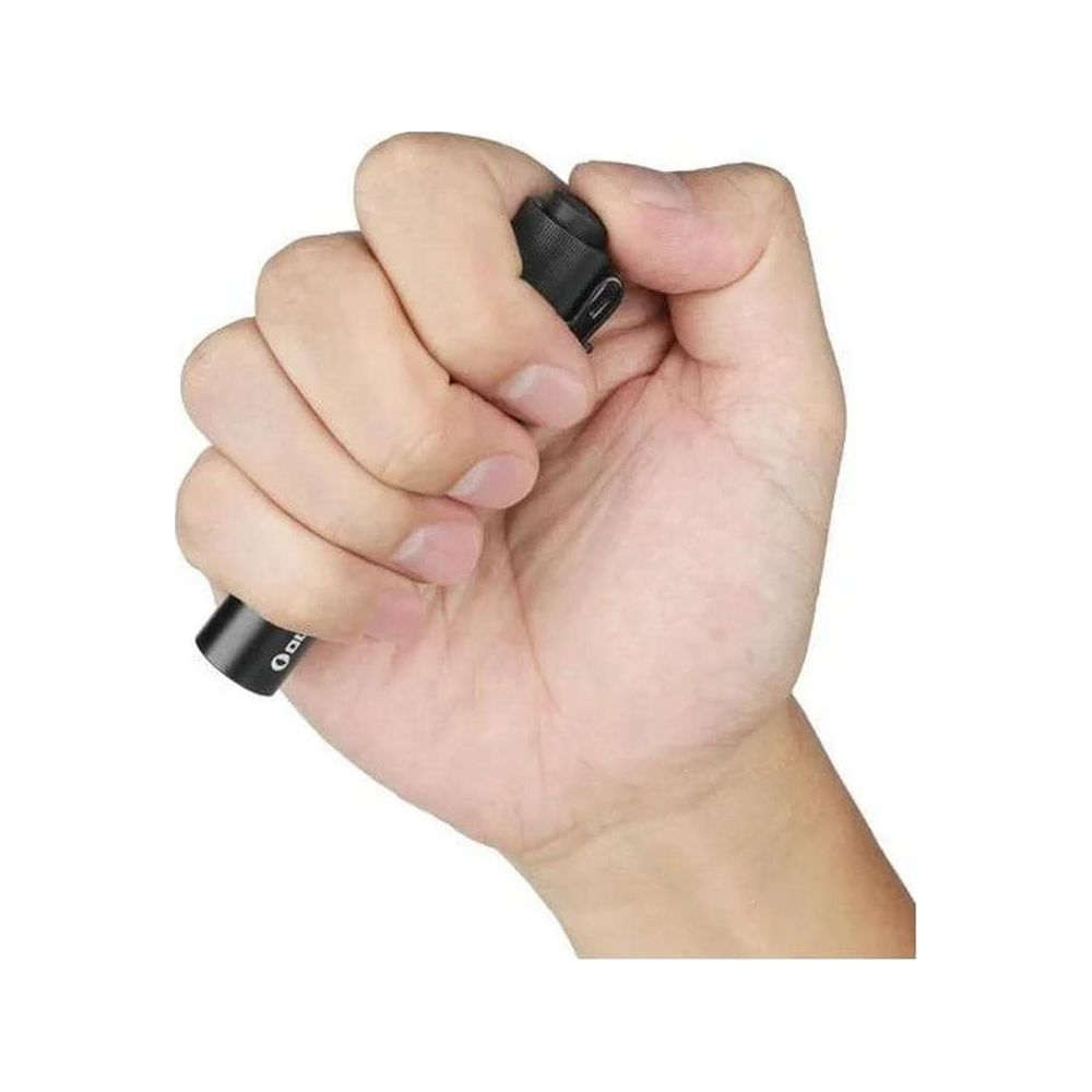 Una mano sostiene una pequeña linterna negra con un puerto USB.