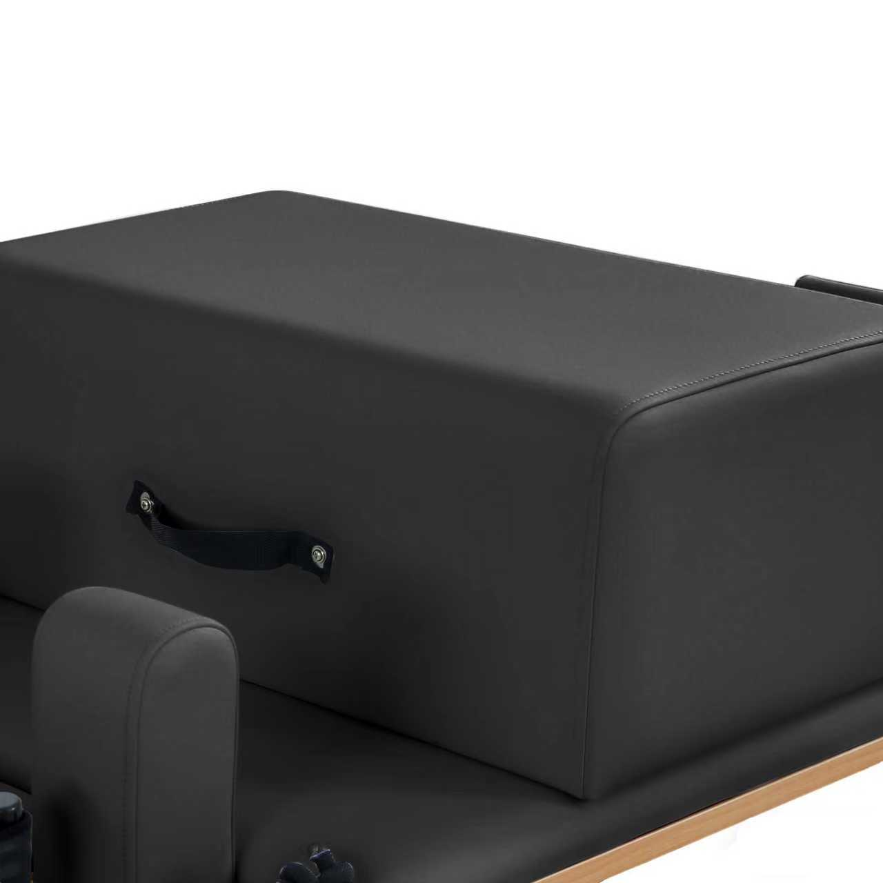 Schwarze Pilates-Box mit Griffen und gepolsterten Armlehnen auf einem Holzrahmen.