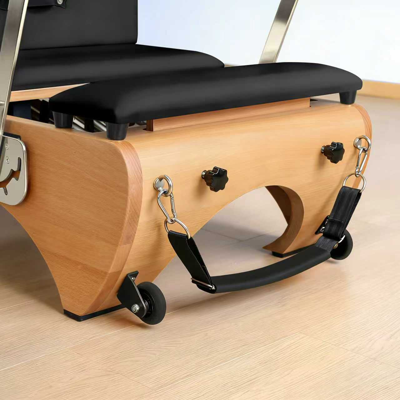 Pilatesgerät aus Holz mit schwarzen Polstern, Rollen und Gurten.