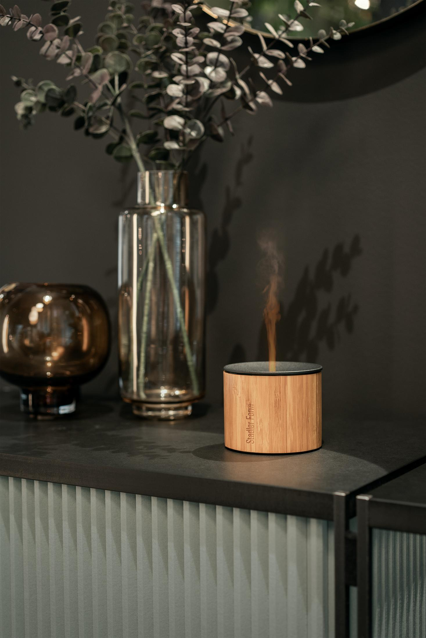 A round wooden diffuser emits steam.