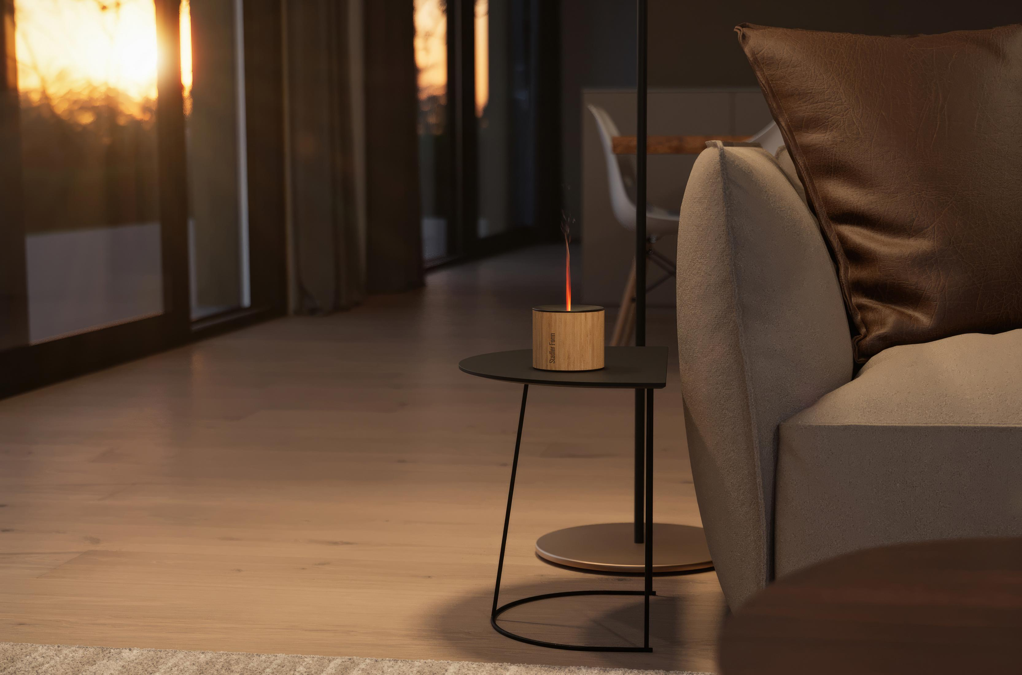 A bamboo fire burner with orange flame on a side table next to a sofa.