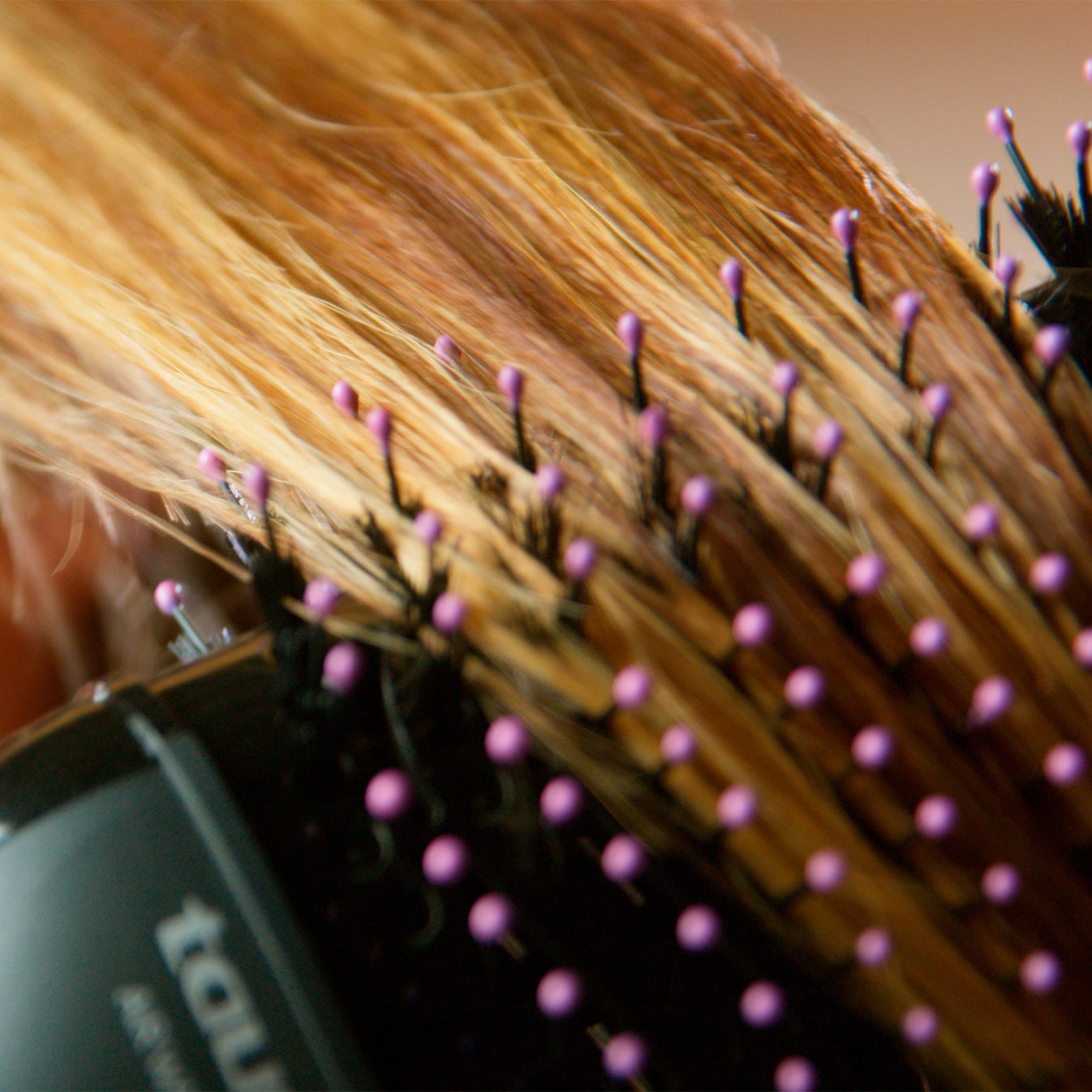 Primo piano di capelli biondi acconciati con una spazzola dalle punte viola.