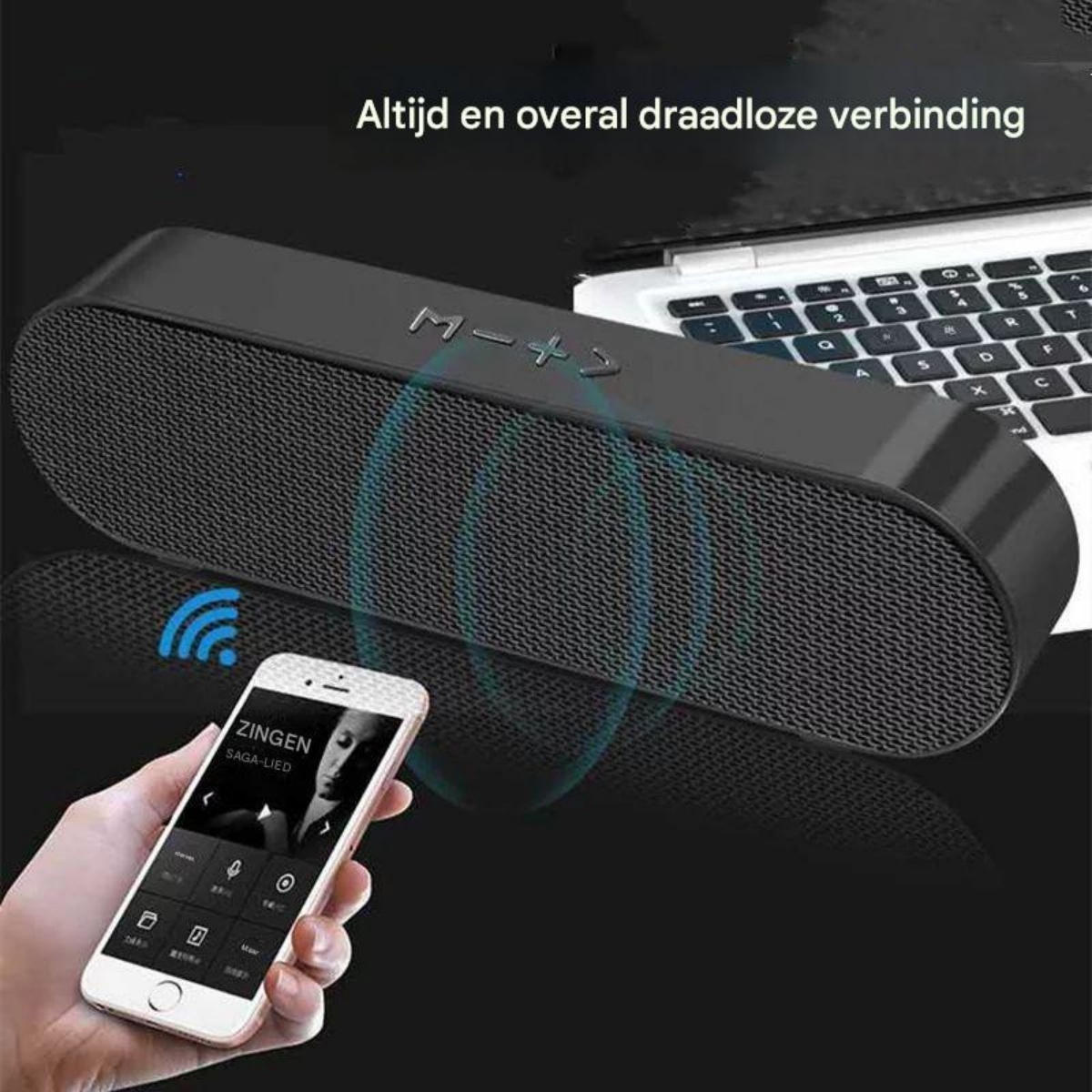 Schwarzer Bluetooth-Lautsprecher, gesteuert von einem Smartphone, neben einem Laptop.