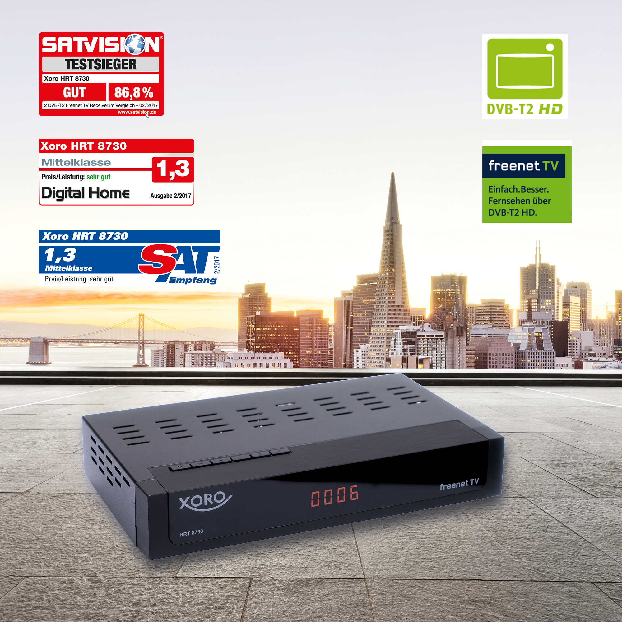 Ricevitore Xoro HRT 8730 DVB-T2 con sigilli e skyline sullo sfondo.
