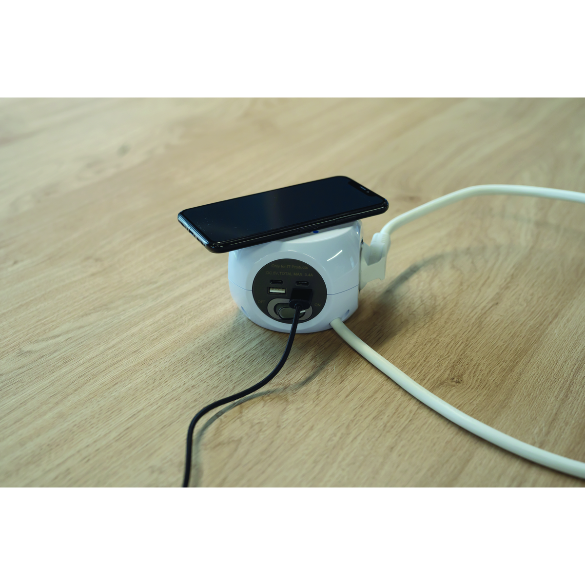 Ein weißer runder Mehrfachsteckdosenadapter mit einem Smartphone und Kabeln.