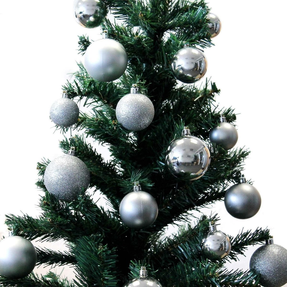 Een close-up van een groene kerstboom versierd met zilveren ornamenten.