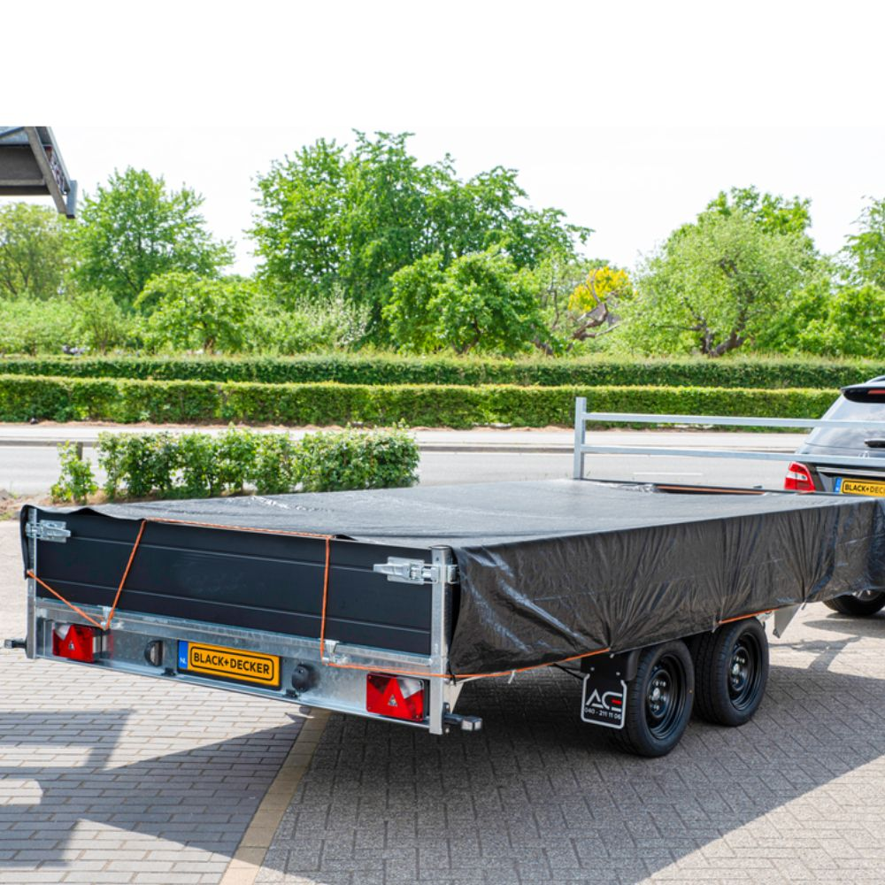 Een zwarte trailer met zeil bevestigd aan een auto.