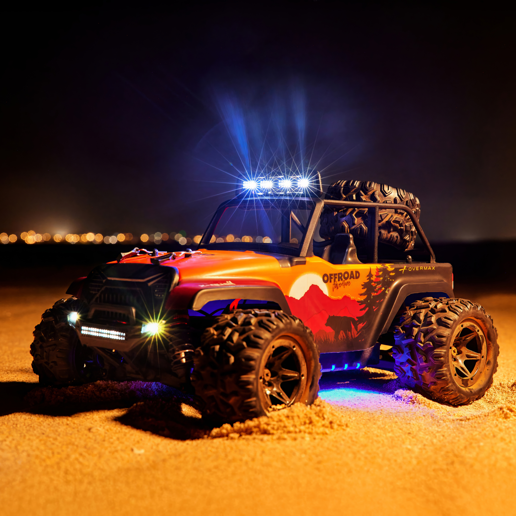 Ein orangefarbenes RC-Offroad-Fahrzeug mit blauen Lichtern auf Sand bei Nacht.