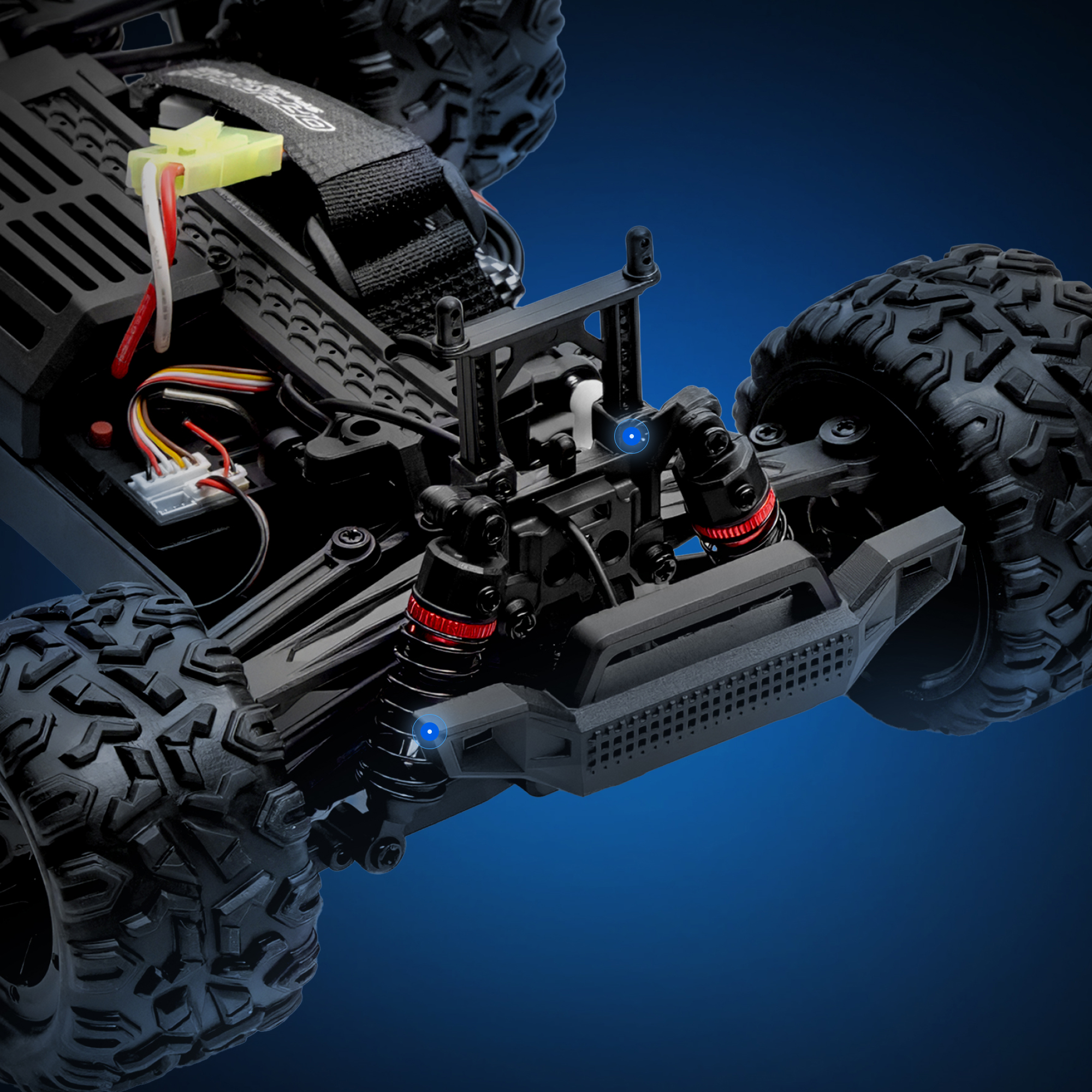 Nahaufnahme des Fahrgestells eines schwarzen RC-Autos mit roten Stoßdämpfern und großen Reifen.