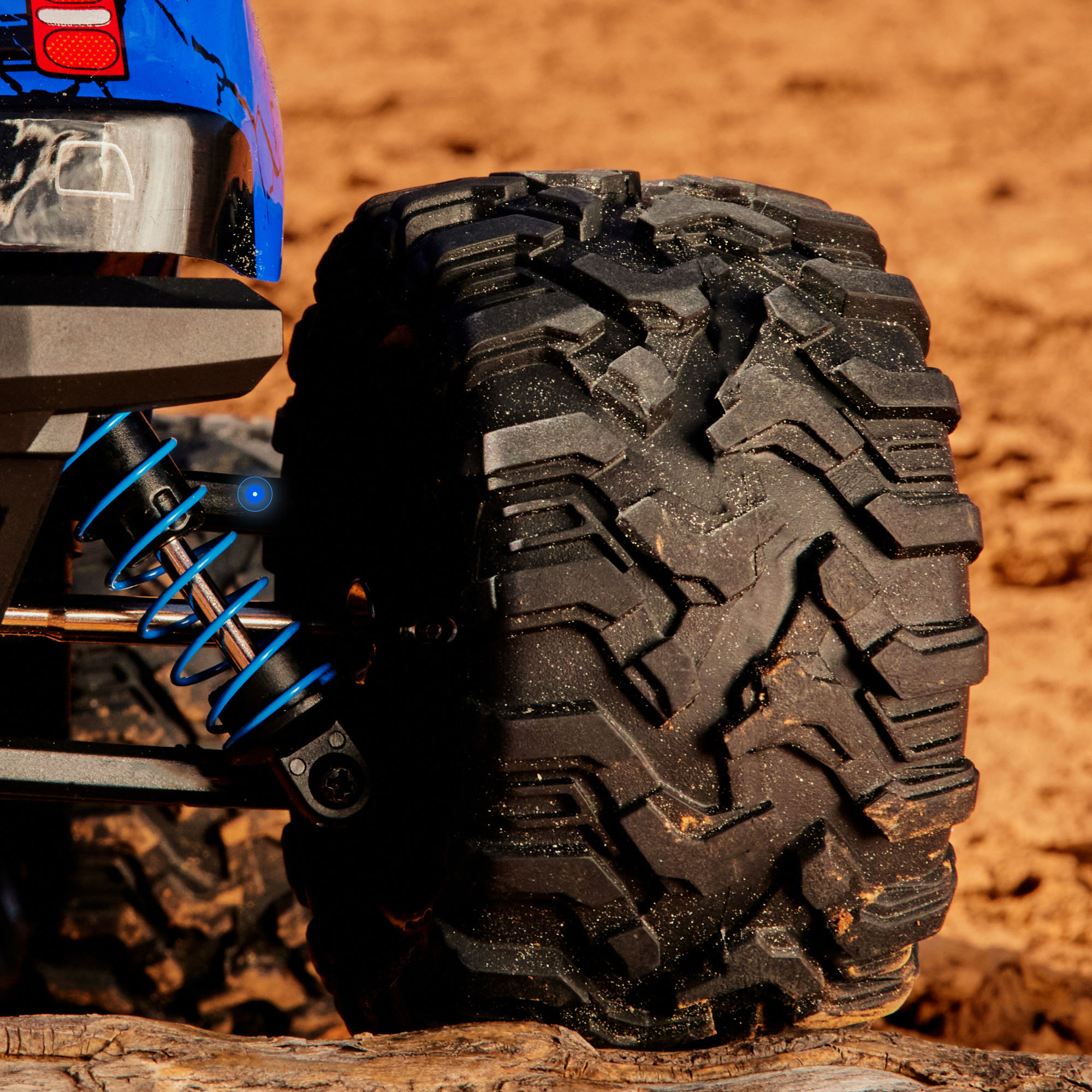 Ein blaues RC-Auto-Rad mit tiefem Profil auf Sand und Holz.