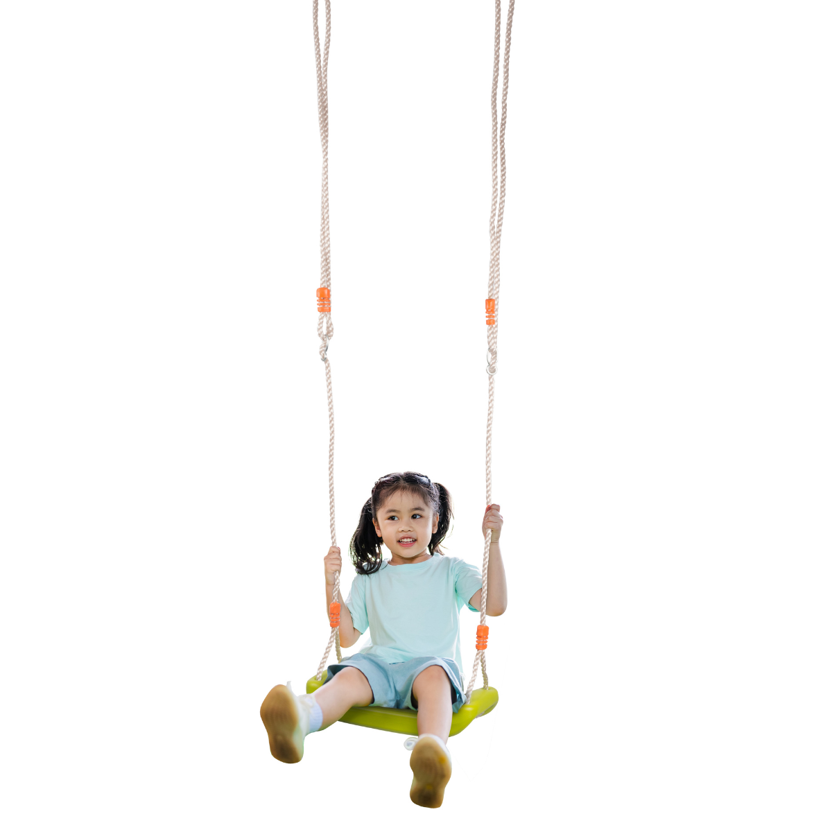 A young girl is swinging on a green swing, wearing a light blue t-shirt and shorts.