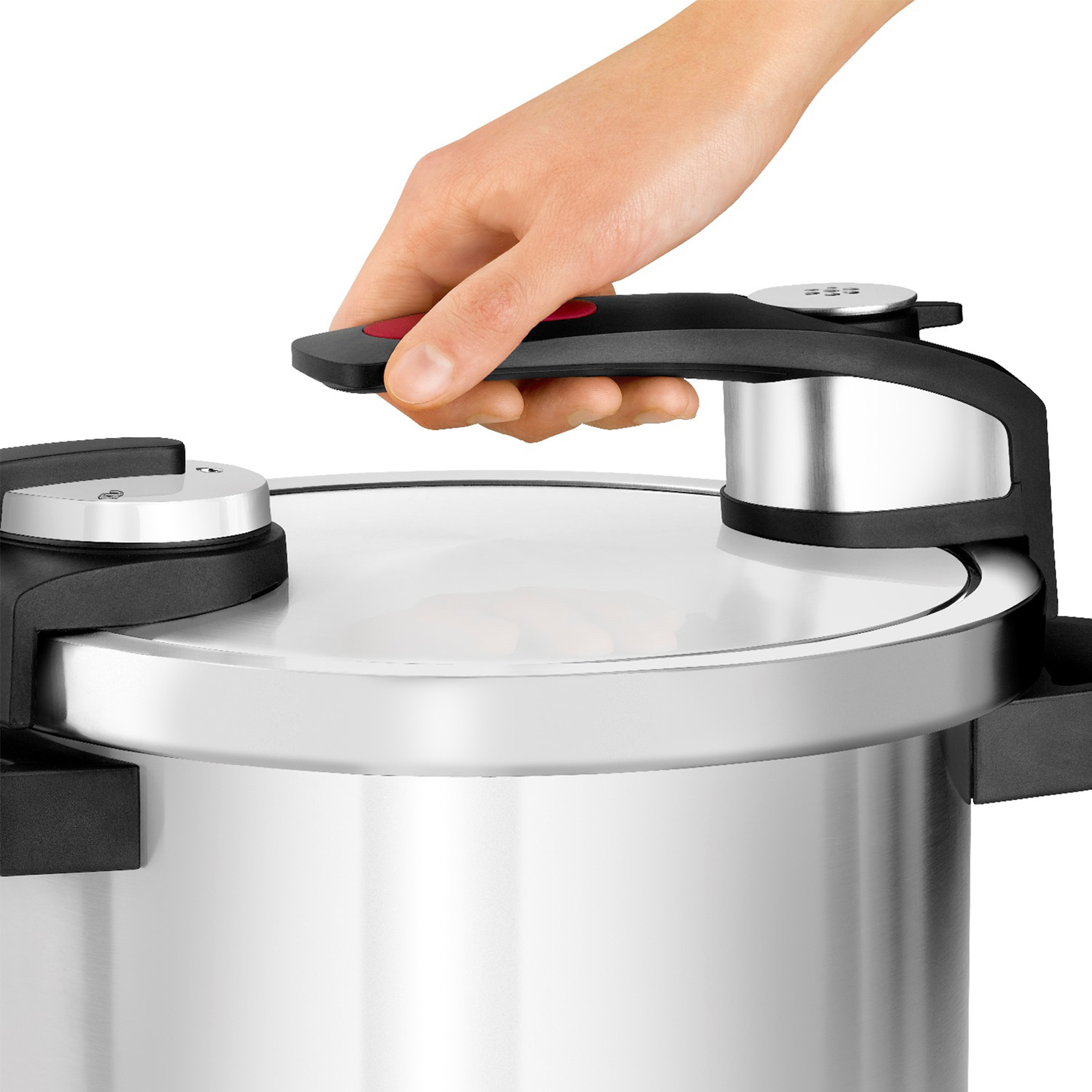 Eine Hand greift nach dem Griff eines Schnellkochtopfs mit rotem Akzent.