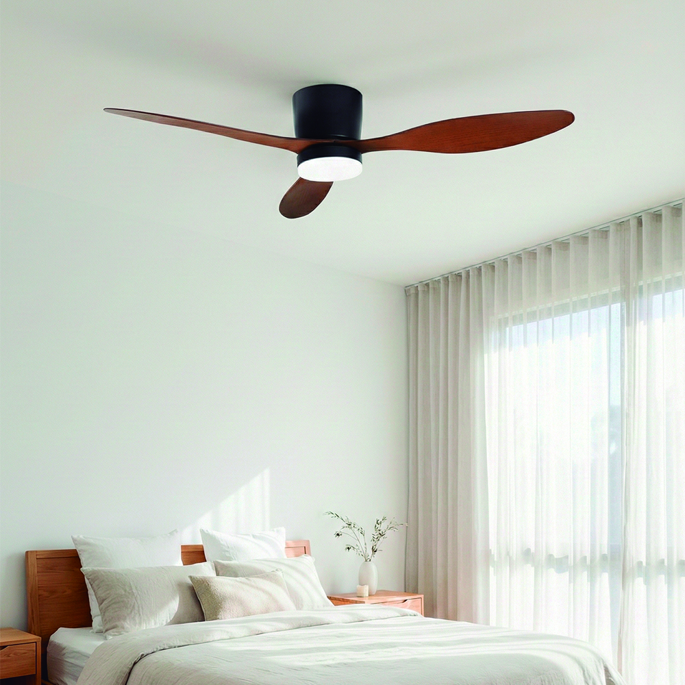 Un ventilador de techo negro moderno con aspas de madera sobre una cama.
