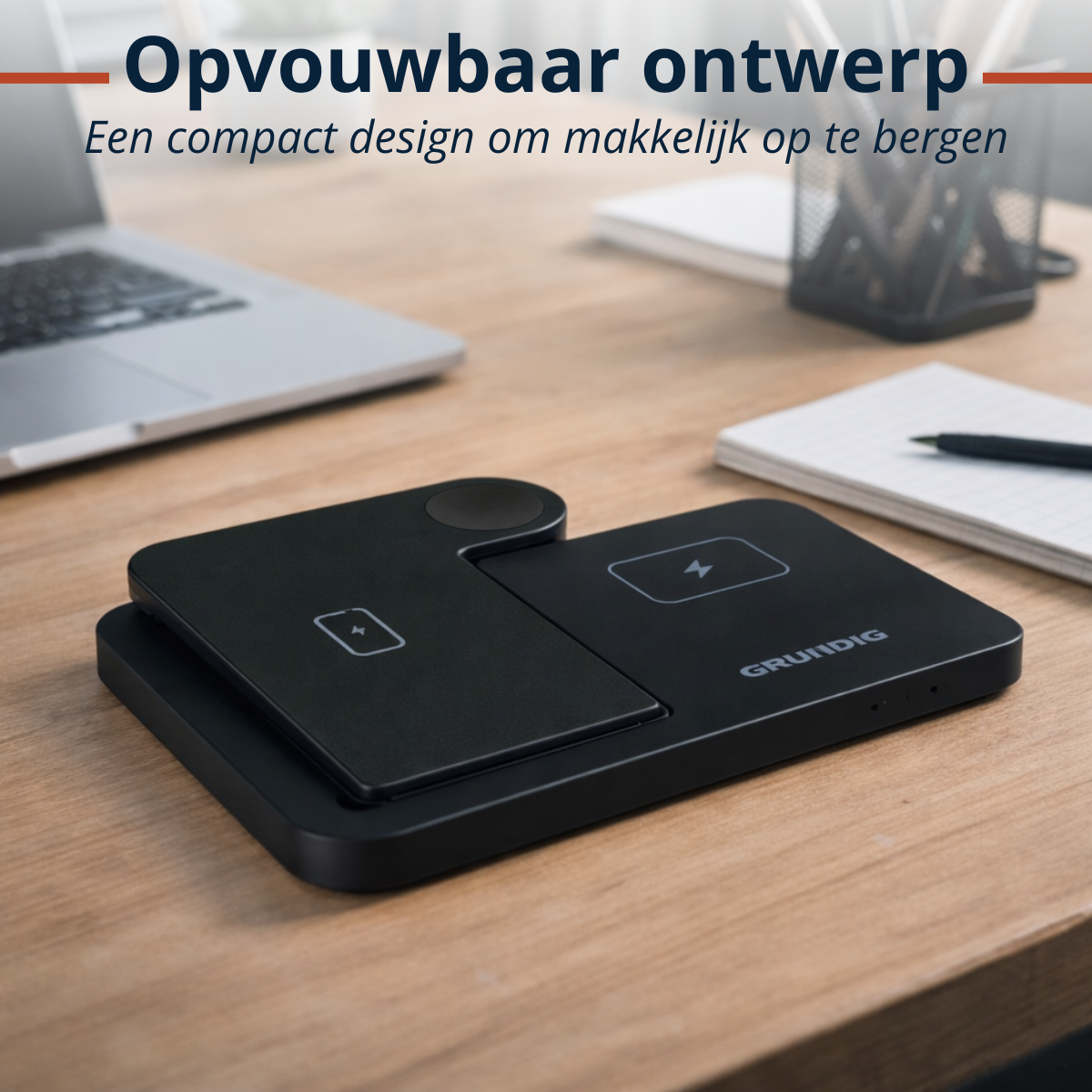 Een zwarte, opvouwbare oplaadpad met laptop en notitieboek op een houten bureau.