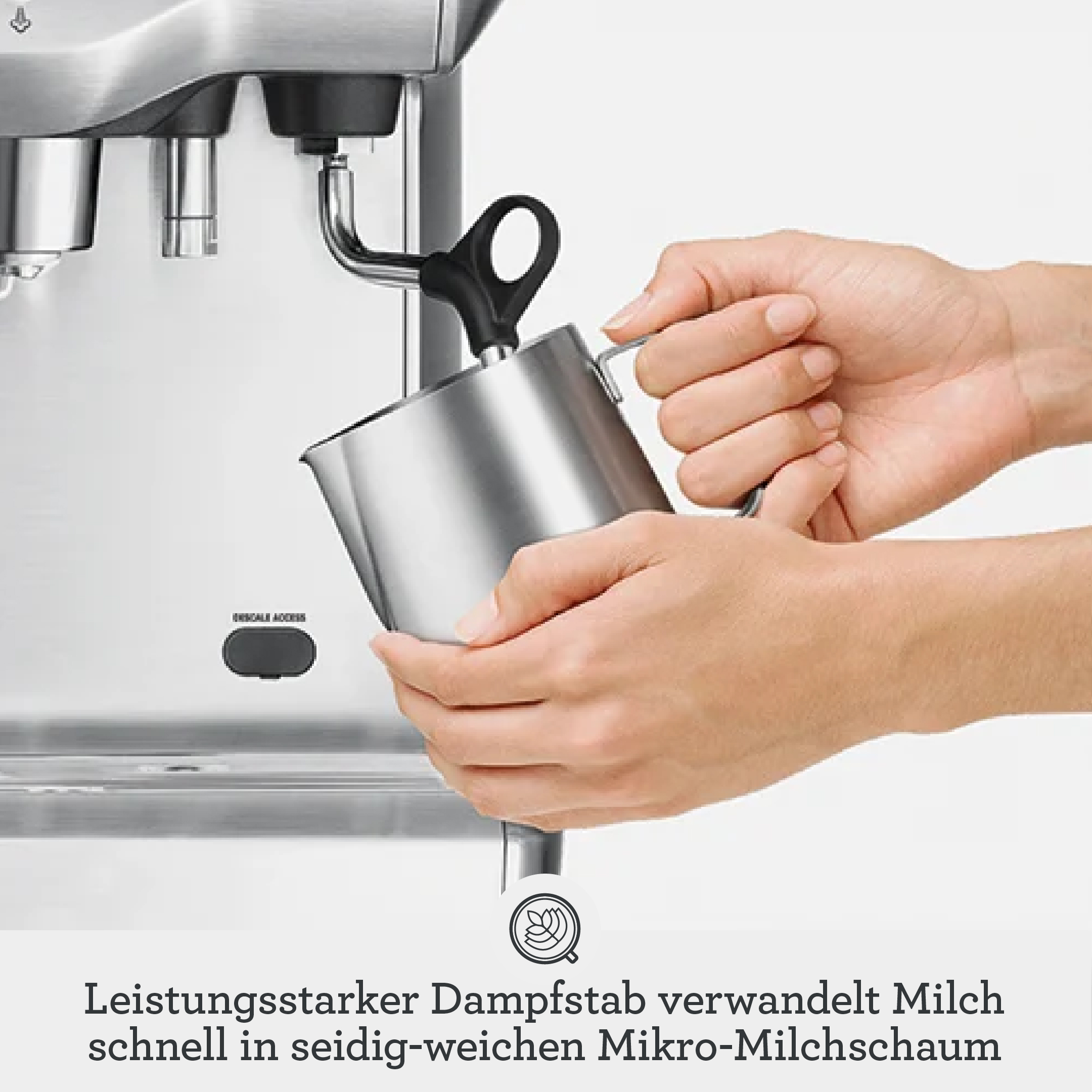 Hände schäumen Milch mit einem silbernen Espressomaschinenstab in einem Metallkännchen auf.