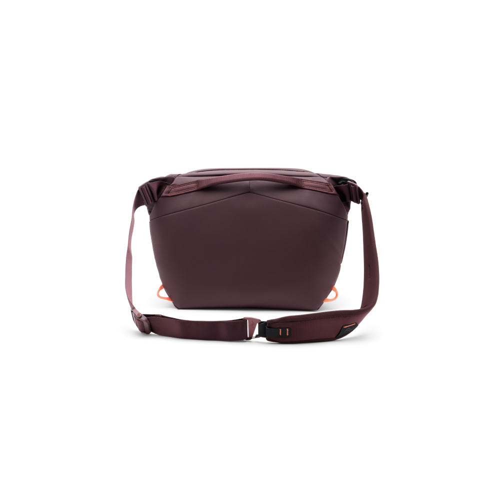 Een donkerrode crossbody tas met riem en oranje accenten.