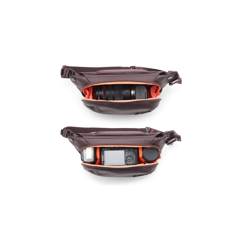 Bruine cameratass met oranje voering, met camera, lens en flitser.