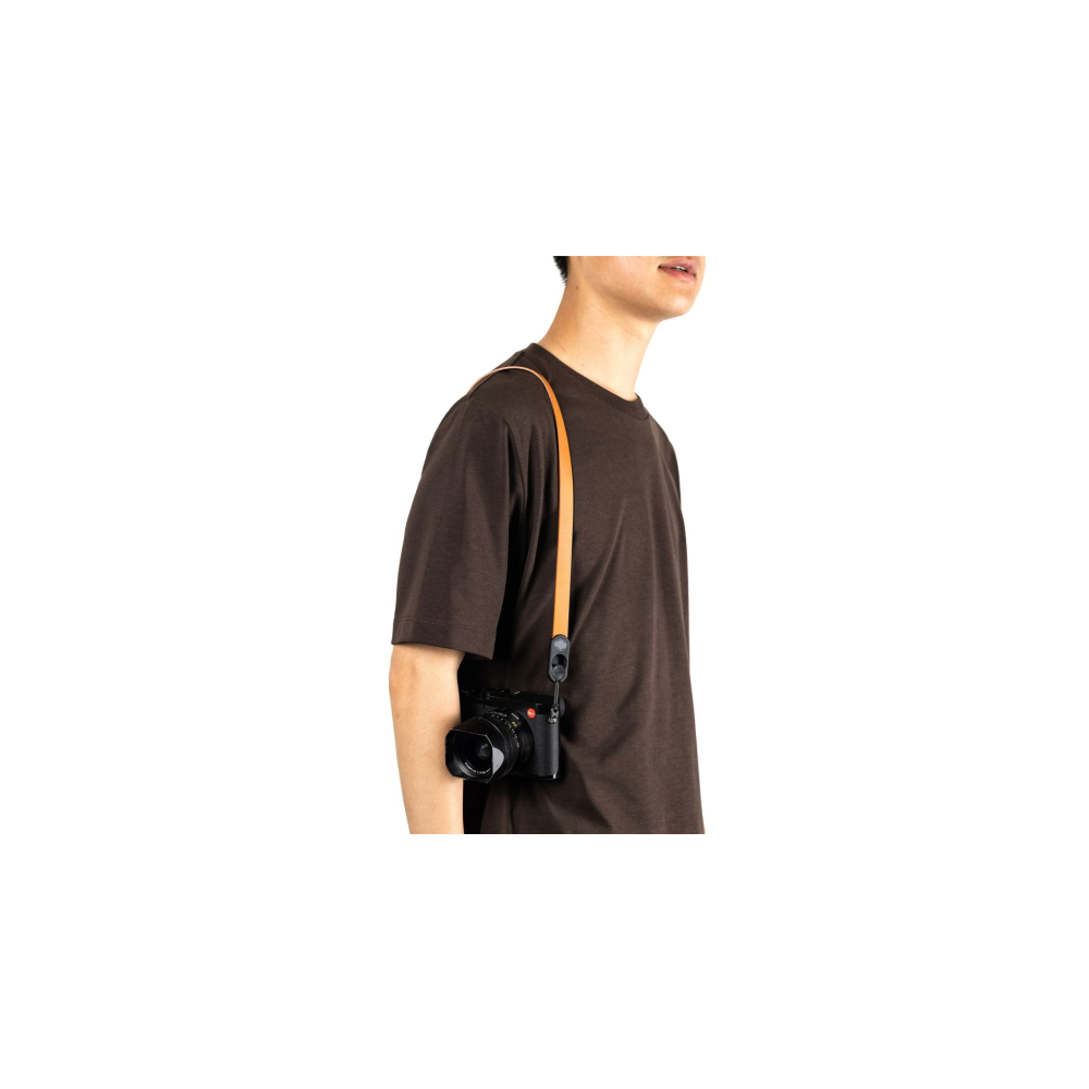 Man in bruin T-shirt met camera om nek en bruine leren riem.