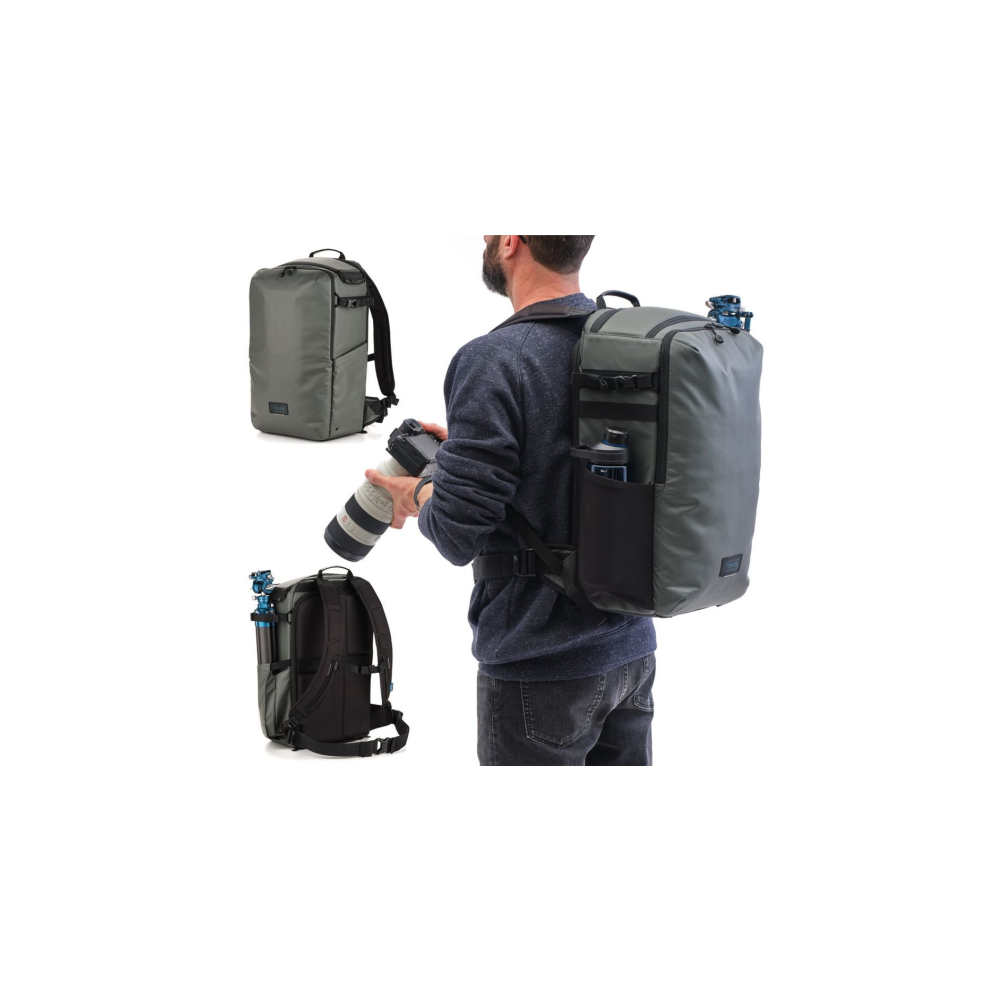 A man wears a grey backpack with a camera. Two other backpacks are visible.