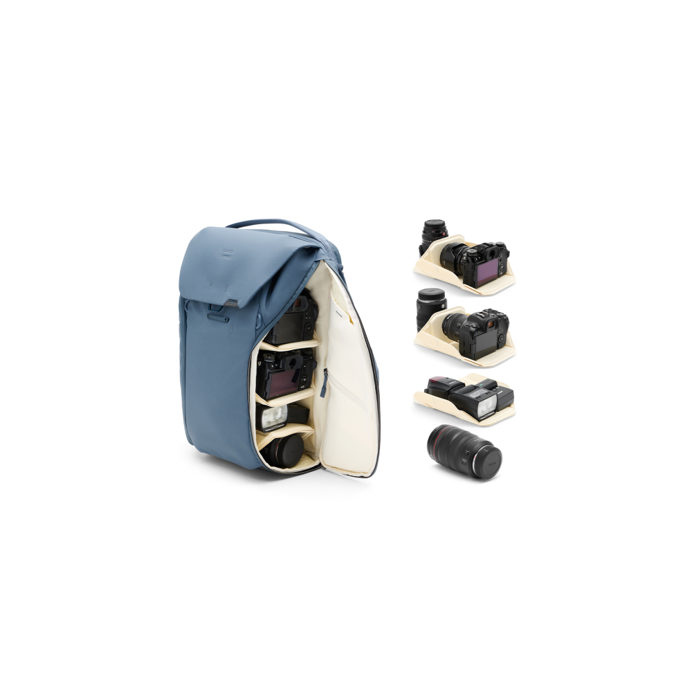 Blue backpack open, showing cameras, lenses and flash inside. Other gear on white background.