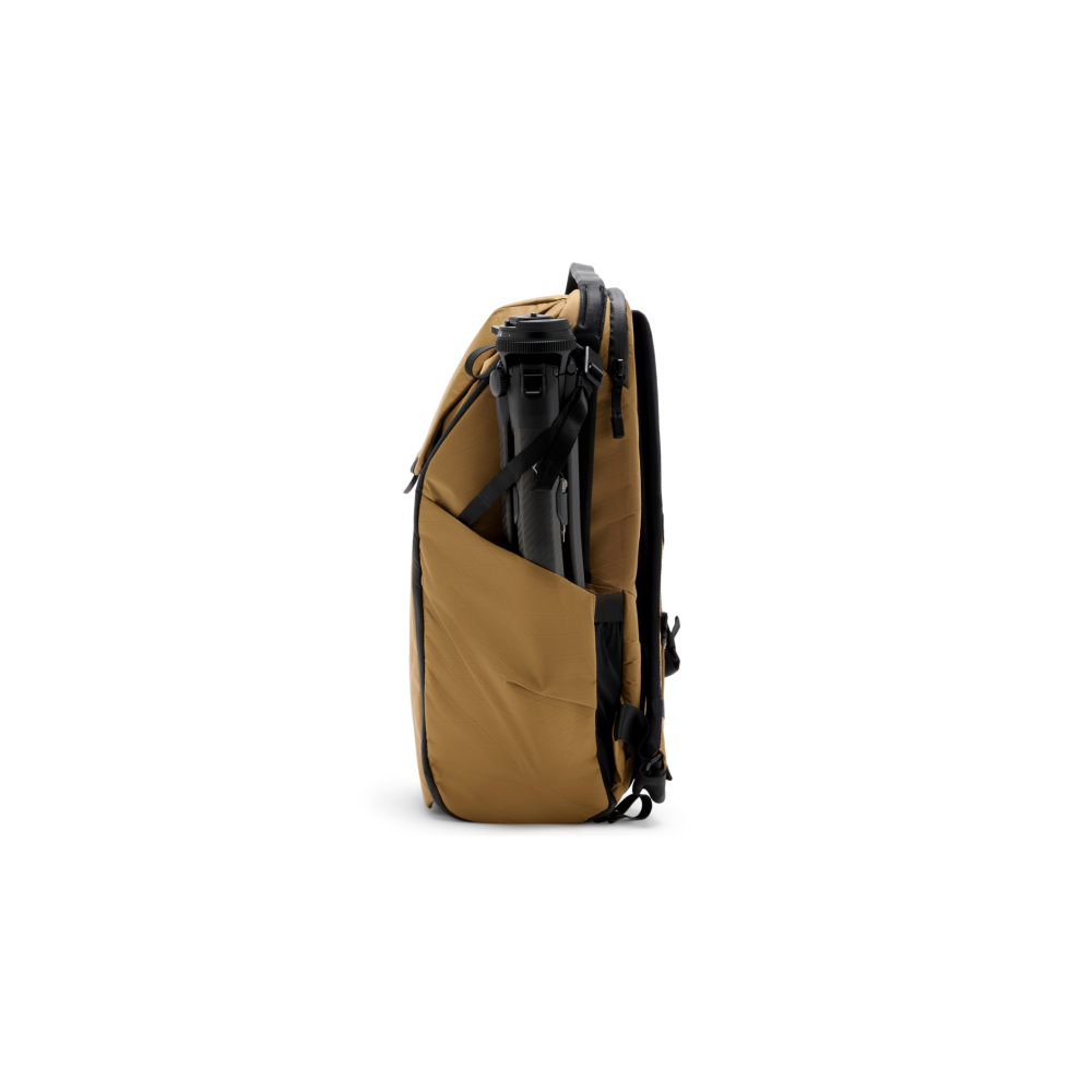 A brown backpack with a black tripod in its side pocket.