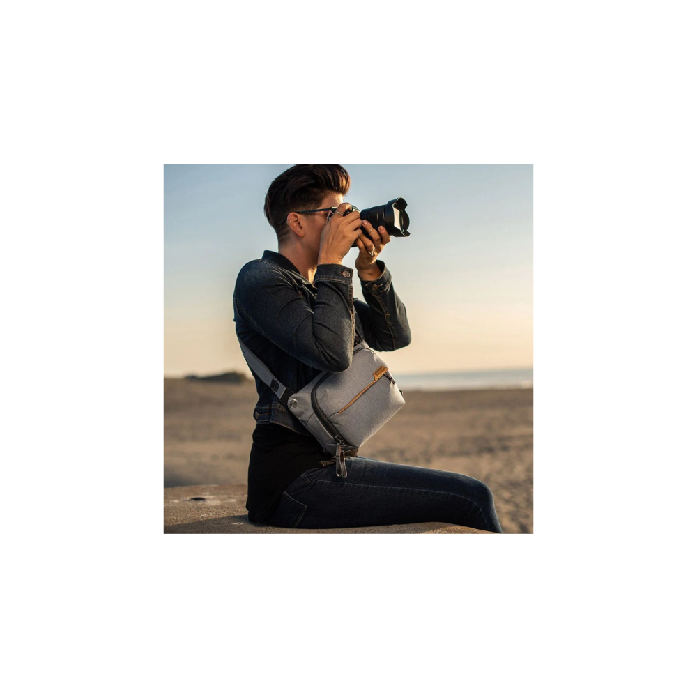 Persoon in spijkerjack maakt foto met camera op strand.