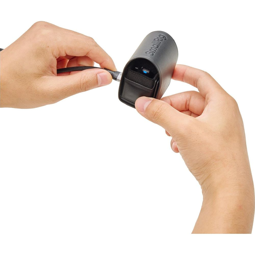 Hands connect a black cable to a black SmallRig device with a blue light.