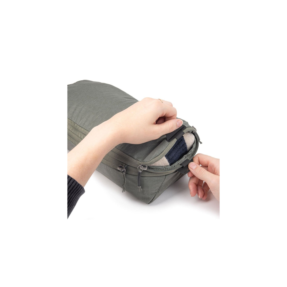 Hands zipping a green bag revealing striped socks inside.