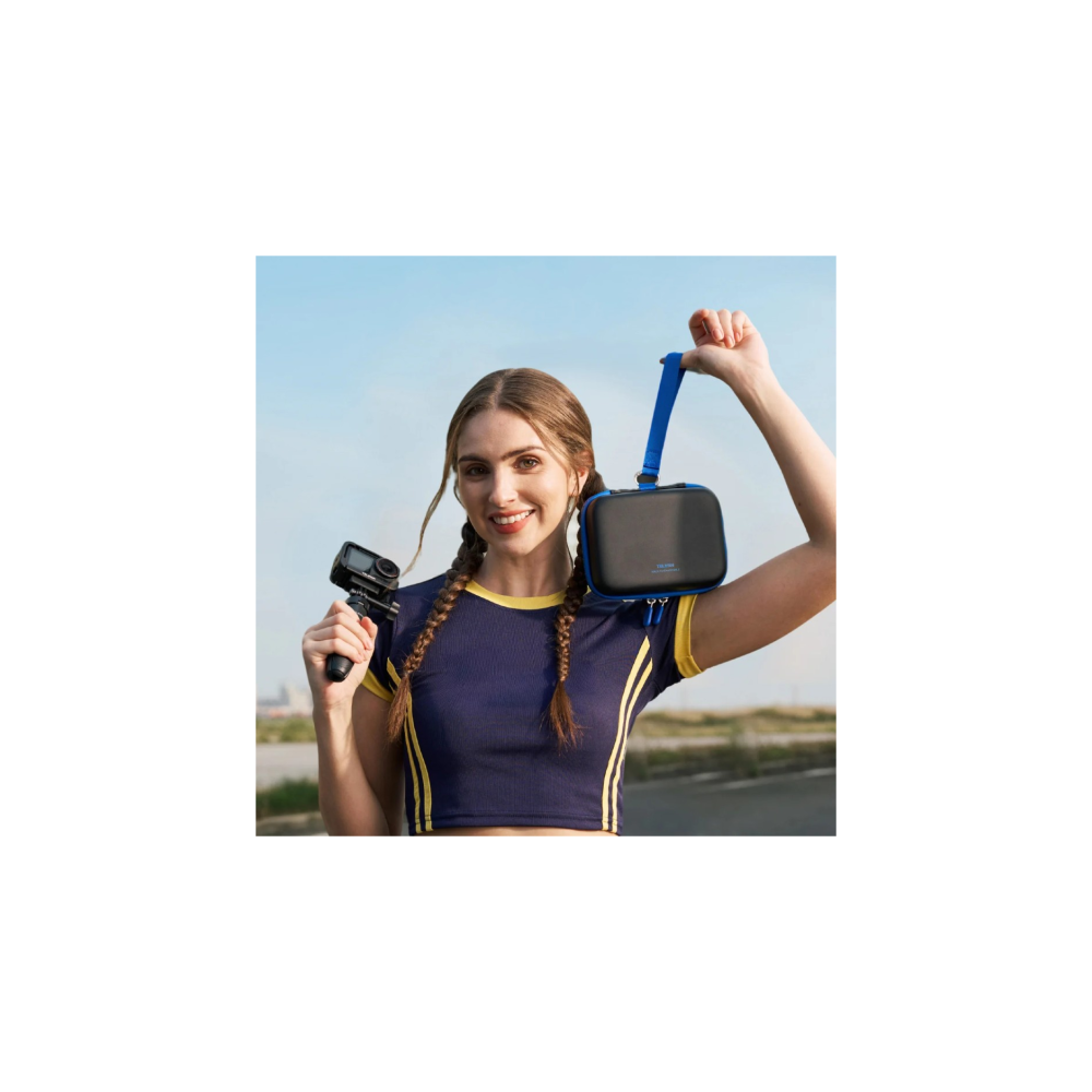Woman in blue shirt with yellow trim holds action camera and black case with blue strap.