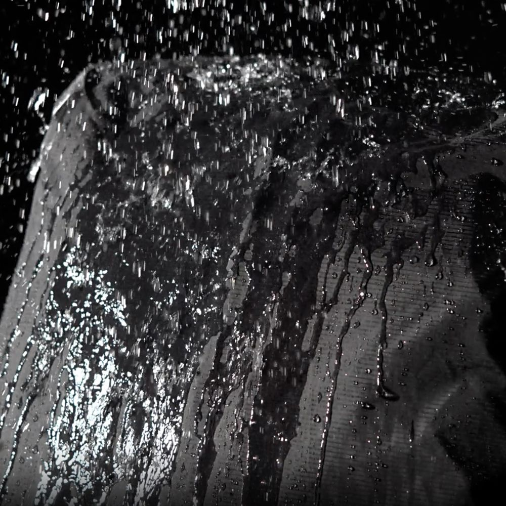Waterdruppels vallen op donker, getextureerd materiaal.