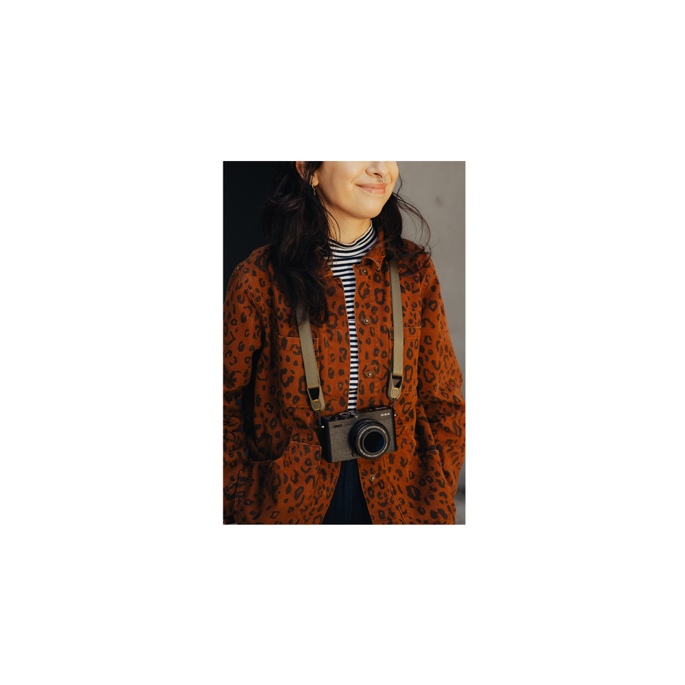 Een vrouw met een luipaardprint shirt met een camera om haar nek.