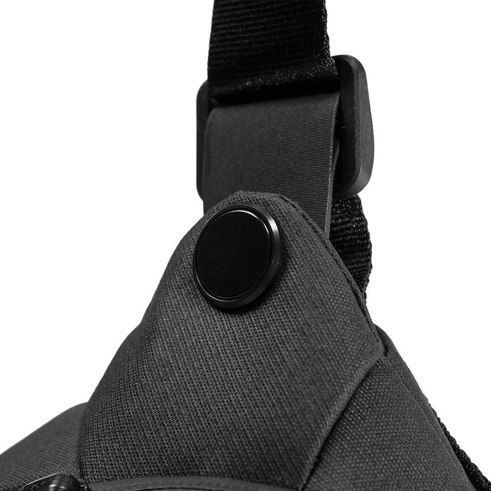 Close-up van een zwarte tas met een zwarte knop en riem.