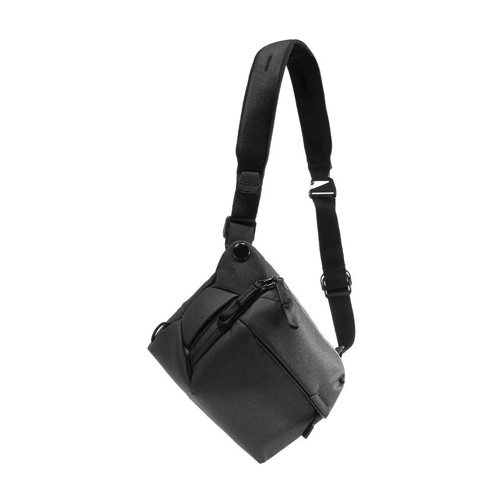 Een donkere, schuine crossbody tas met band, geïsoleerd op witte achtergrond.