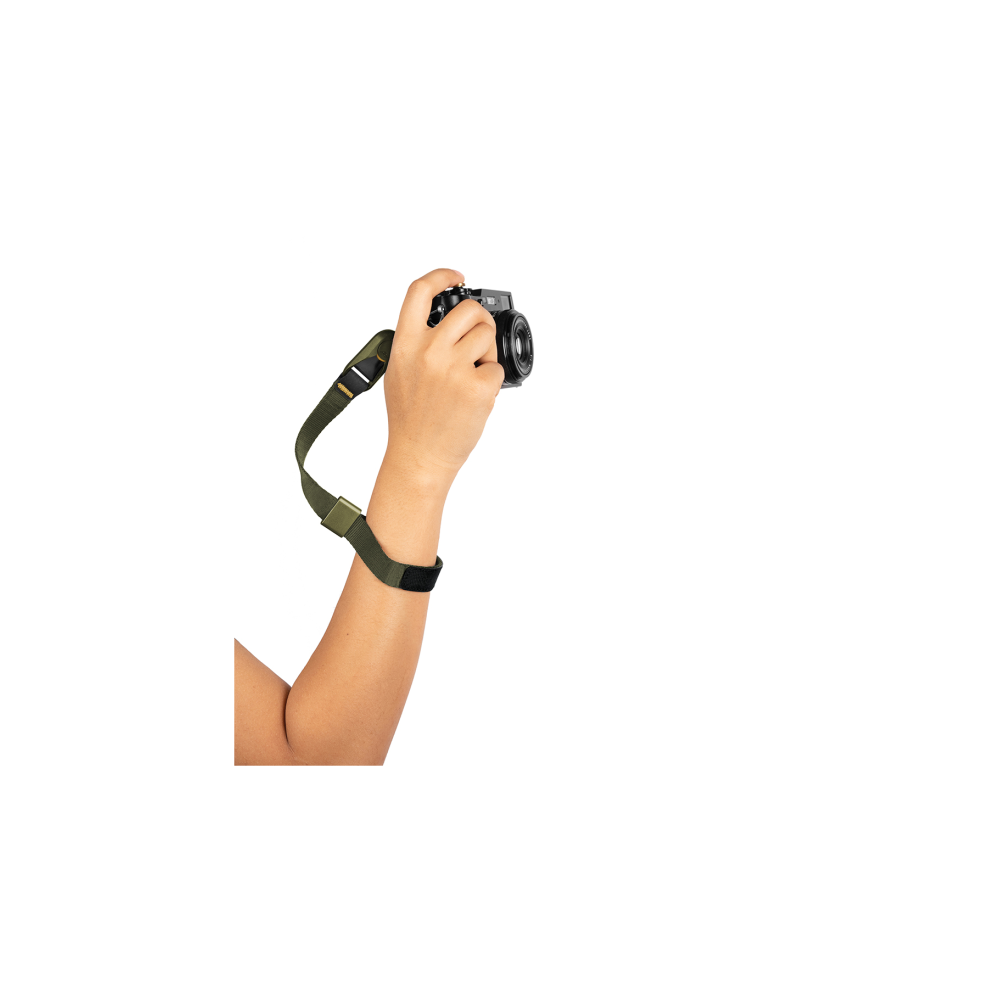 Een hand houdt een camera vast met een groene riem.
