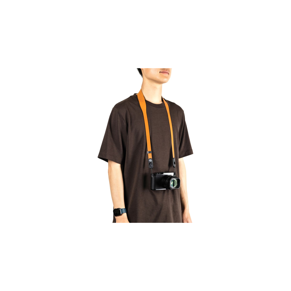 Een persoon draagt een bruin t-shirt met een camera aan een oranje band.
