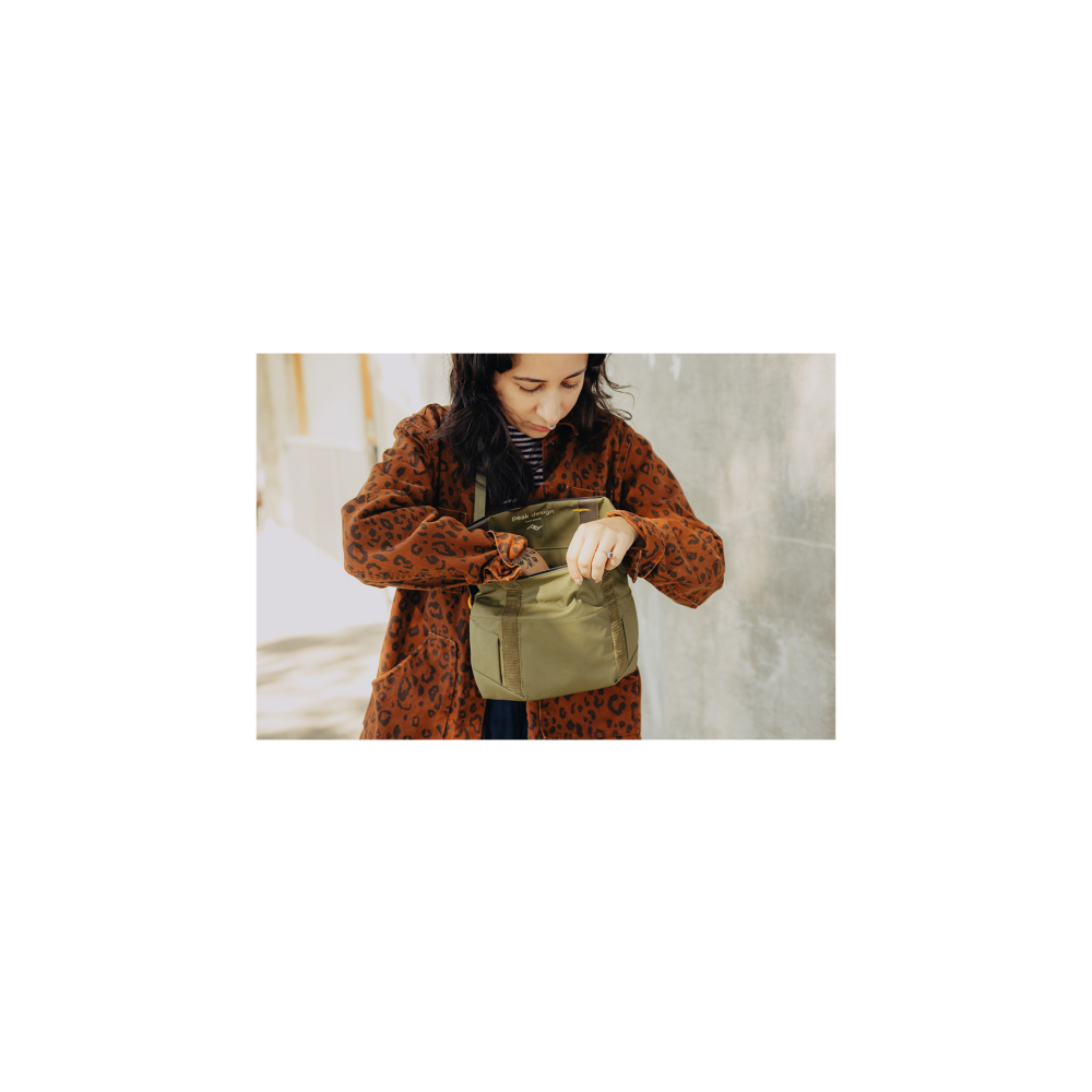 A woman in a leopard print coat searches in a green bag.
