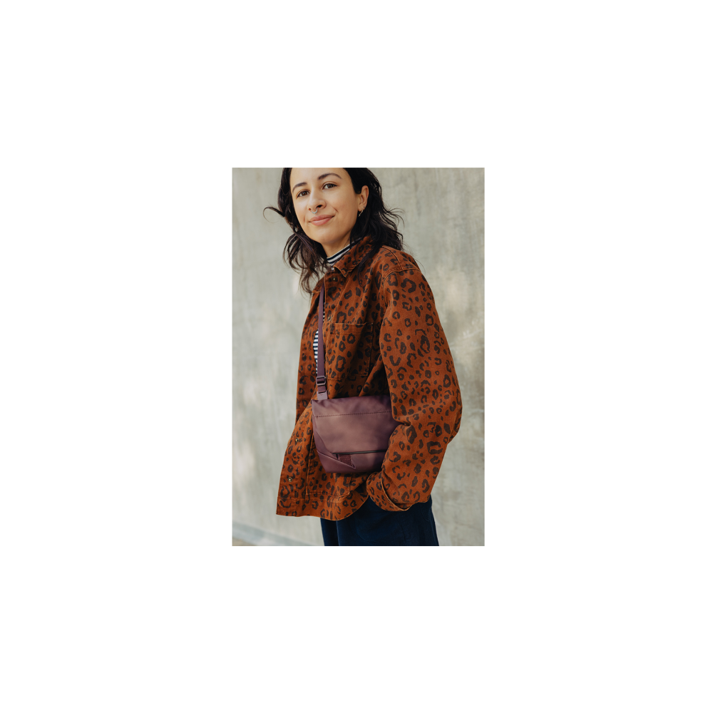 A woman with dark hair wears a brown leopard print jacket and a crossbody bag.