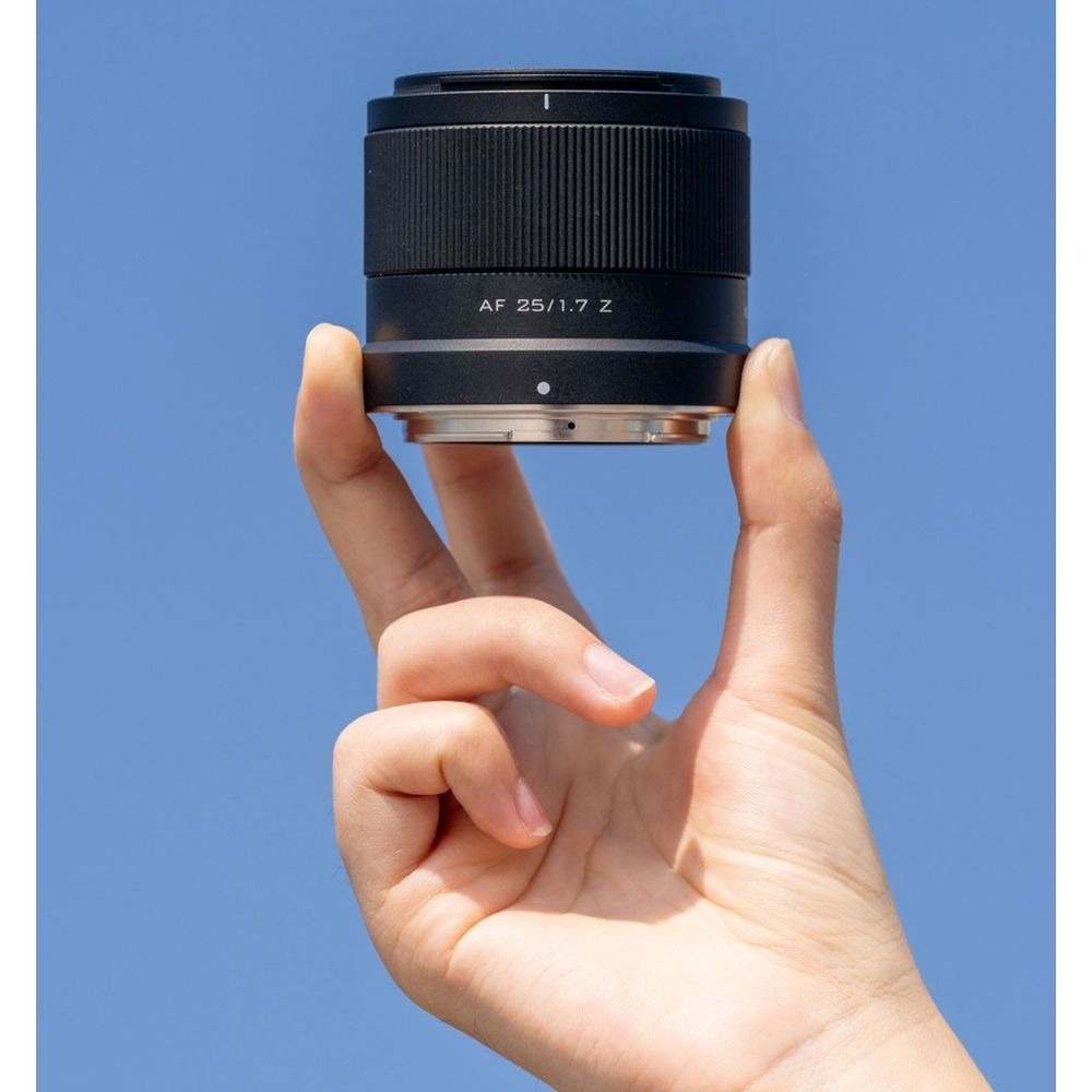 Una mano tiene un obiettivo della fotocamera nero su sfondo blu.