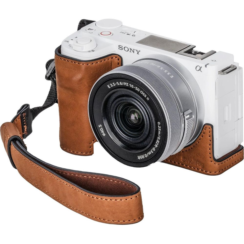 White Sony camera with a brown leather case and wrist strap.