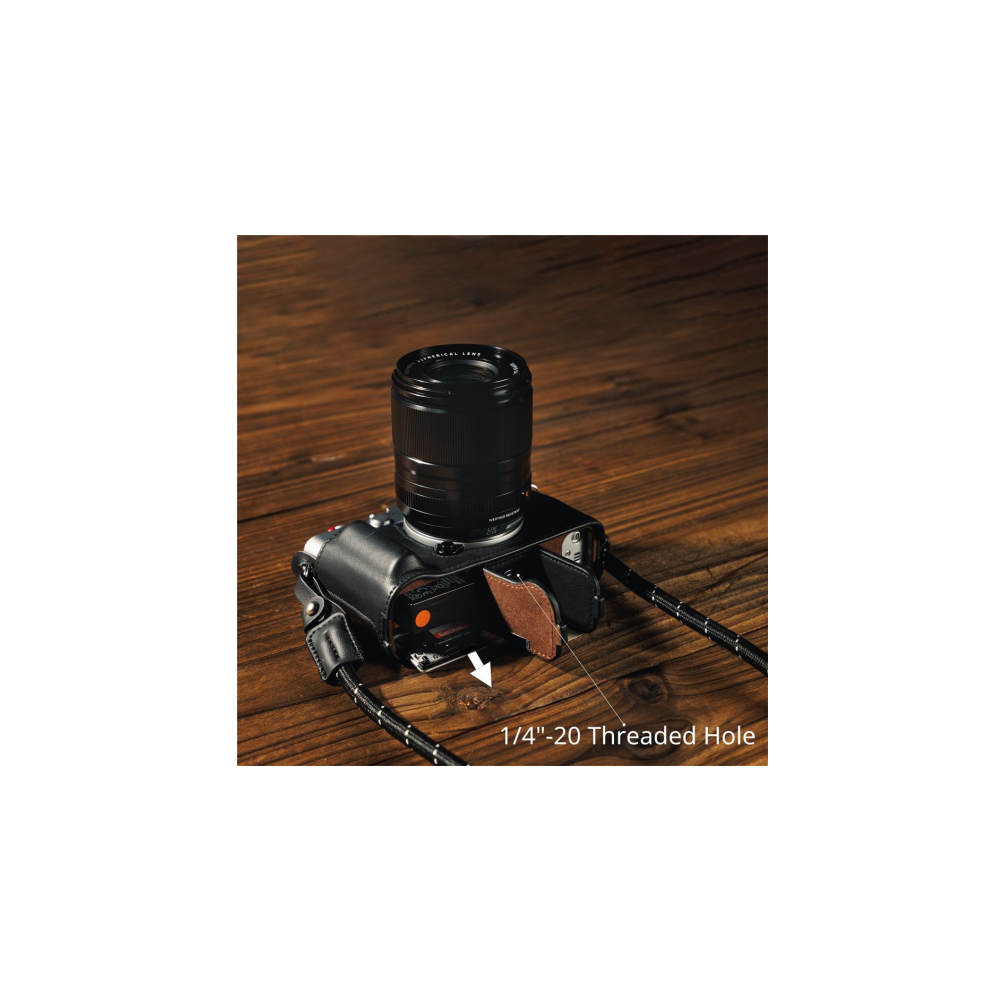 A black camera with a lens and strap on a wooden table. An arrow points to the threaded hole.