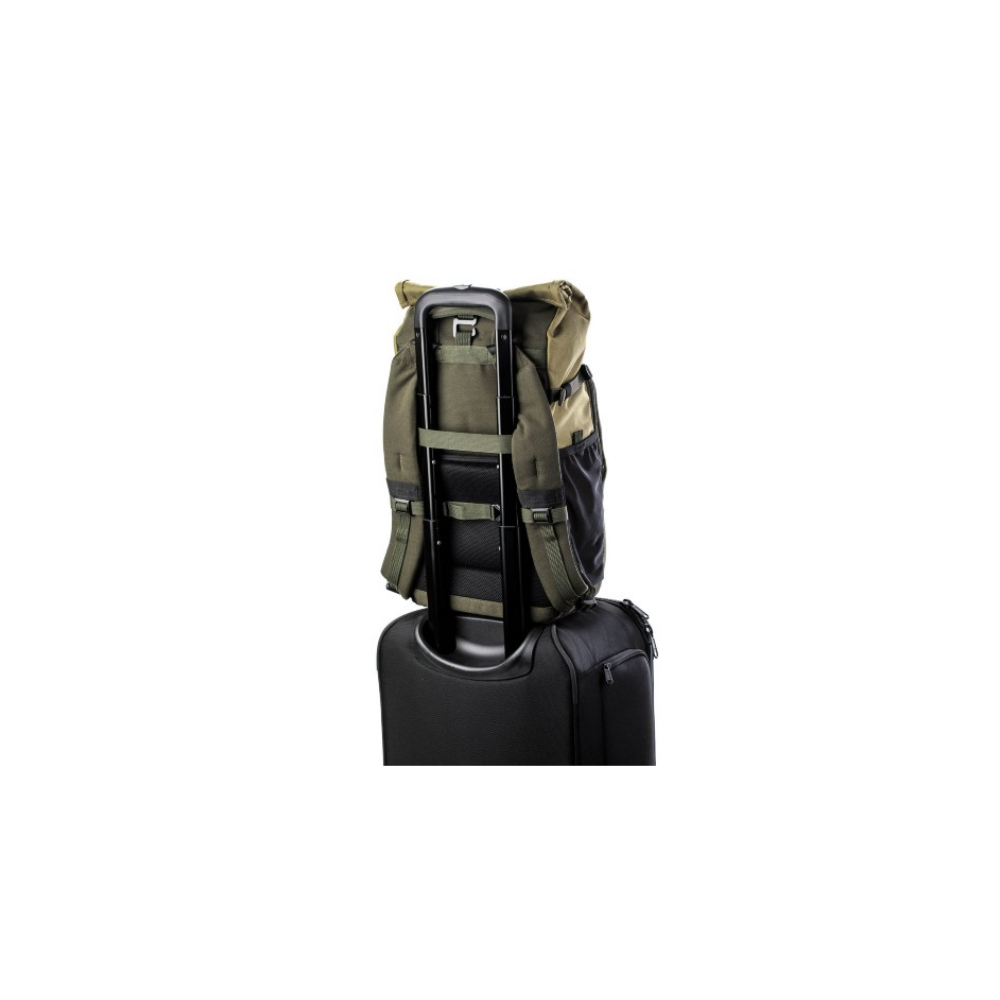 A green backpack rests on top of a black rolling suitcase with an extended handle.