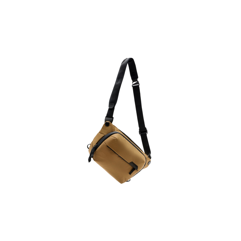 Een bruine crossbody tas met zwarte band, geïsoleerd op witte achtergrond.