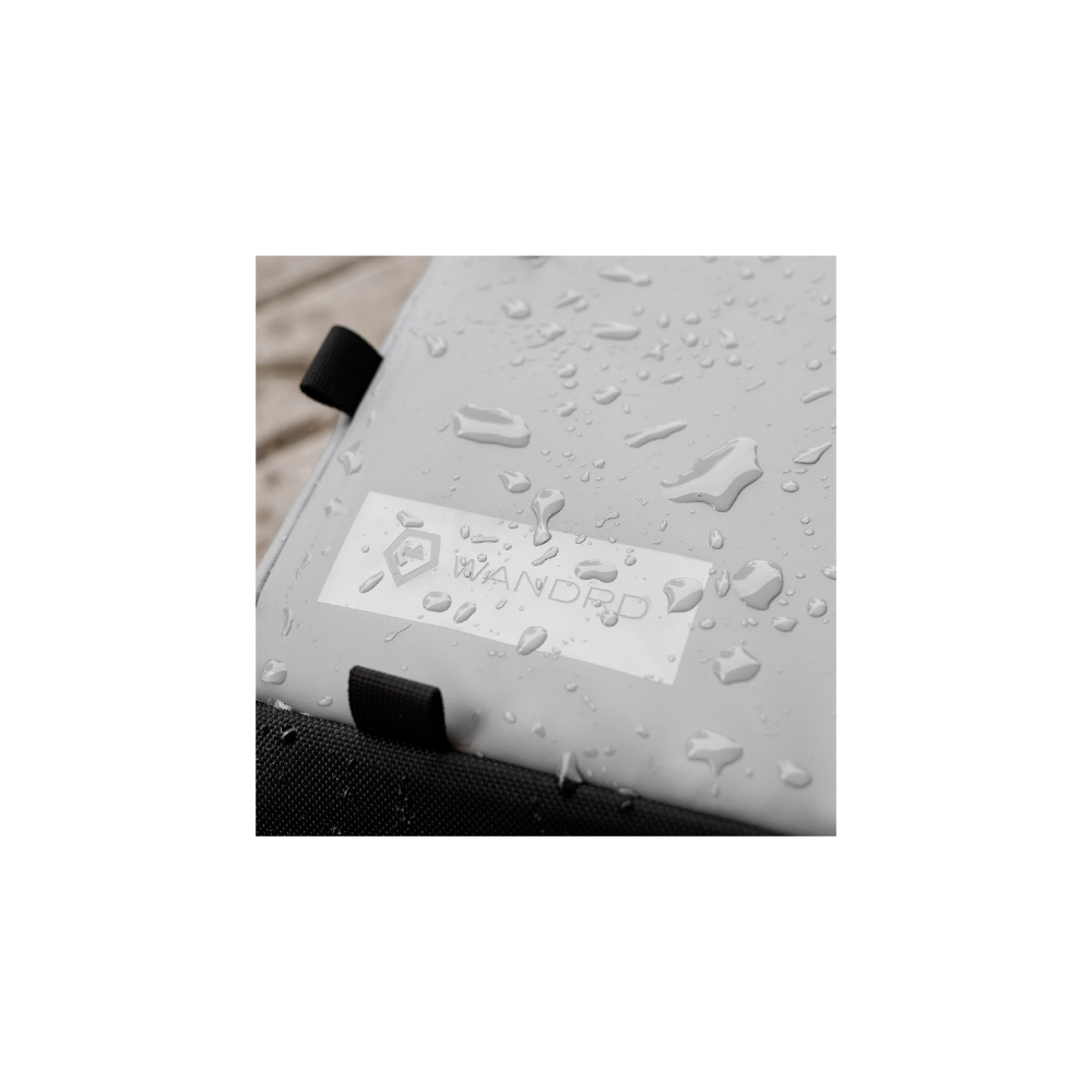 Grijze tas met WANDRD-logo, bedekt met waterdruppels.